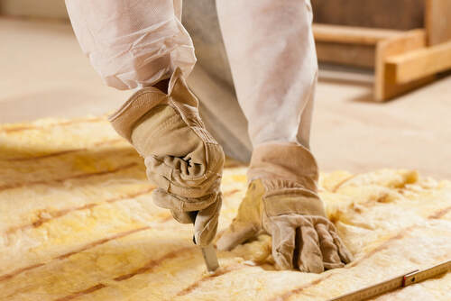 Greenwich Insulation contractor cutting some glass wool as material for thermal insulation of a new building